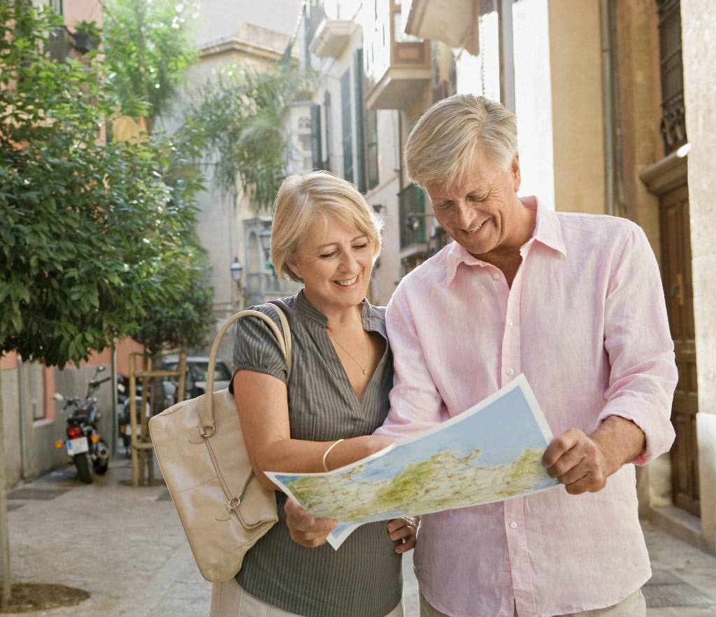 Happy retired couple travelling looking at map tablet