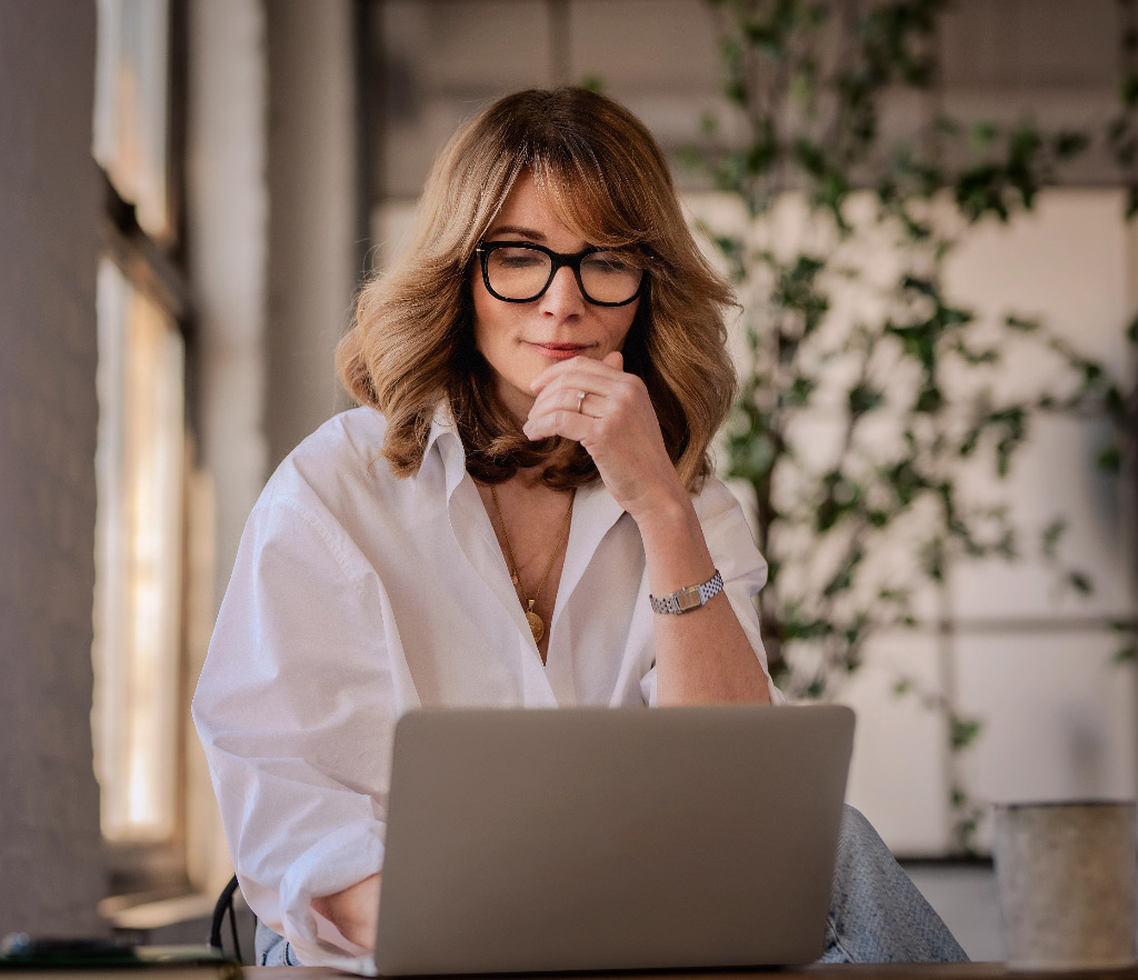 Middle aged woman reviewing strategy with laptop tablet