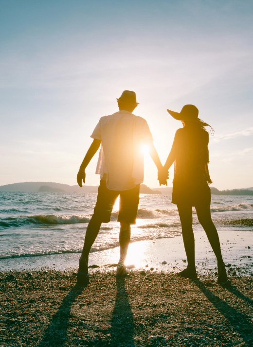 Successful couple on the beach at sunset looking at the ocean