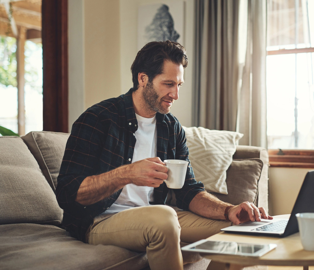 Young man with coffee reviewing financial plan tablet